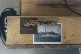 A black and white photo of a forest on a wooden table, with a rusty metal piece and cable beside it.