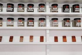 Shelves with labelled jars containing soil samples and numbered brown tiles displayed below.