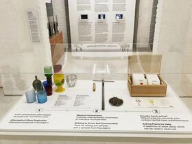Exhibit with colourful glassware, soil samples, and plant seeds. Informational text on the wall in the background.