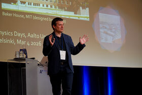 A person in a dark suit gives a presentation at Aalto University in Helsinki. A slide shows 'Baker House, MIT'.