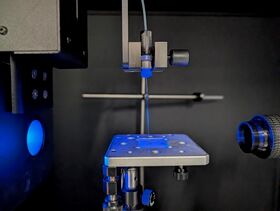 Lähikuva tarkkuusinstrumentista metallisella alustalla ja sinisellä valaistuksella laboratoriossa.