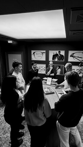 Group of people around a display table of eyeglasses in a modern showroom