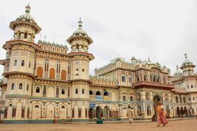Ornate cream and red palace-like building with domes, arches and towers, people walking in front