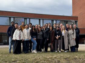 Group of 22 people standing next to each other and smiling