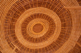 Close-up of a round woven basket in light brown, seen from above with concentric rings