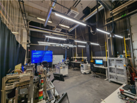 Industrial lab with machines, cables and computer workstations under bright ceiling lights