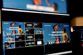 Computer screens showing a live panel discussion layout with kite surfers and event branding