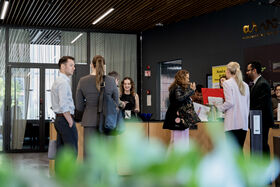 People in business attire talking at a modern reception desk in a bright office lobby