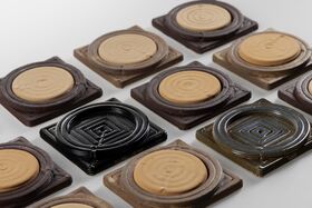Rows of square ceramic tiles with circular and square spiral patterns in beige, brown and black tones.