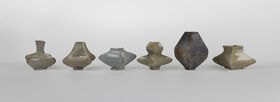 Row of six grey and beige ceramic vases with wide angular bodies on a plain light background.