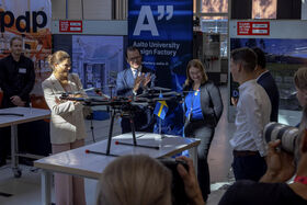Ryhmä laboratoriossa tutkii pöydällä olevaa suurta mustaa dronea, pieni Ruotsin lippu vieressä