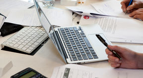 A laptop and papers on a table.