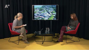 kaksi naista istuu punaisilla tuoleilla studiossa keskustelemassa, taustalla musta verho ja keltainen lattia 