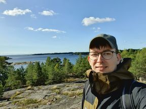 Julius on a cliff near a forrest looking into the camera