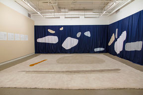 Photo of an art installation consisting of tapestry and fabrics in a gallery space