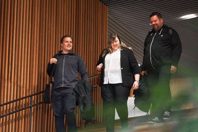 Kolme ihmistä kävelee vierekkäin alas portaita.