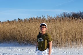 Tutor Minh Duc Pham standing on ice with his student overalls and student cap on.