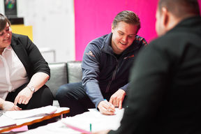 Opiskelijat istuvat pöydän ääressä ja tekevät yhdessä muistiinpanoja.