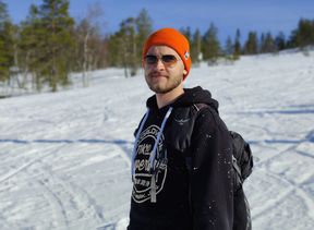 Akseli Rautakorpi kuvattuna lumisessa metsämaisemassa, aurinkolasit päässä.