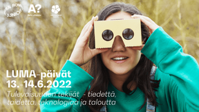 Tyttö katsoo pahvilaatikosta tehtyjen kiikareiden läpi. Taustalla pajukkoa