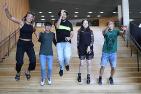 Summer School student group smiling and hopping down the stairs at Aalto's Väre building  