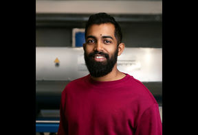 A portrait of Madhawa Basnayaka wearing a red sweater.