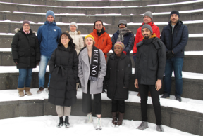 A group of people in coats standing outside on snowy staircase