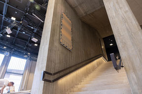 Concrete staircase leading upstairs, a painting hanging on the wall on the left