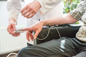 Labratoriossa tutkija mittasi henkilön verenpainetta.