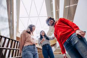 Three students standing together, laughing and looking at the camera.