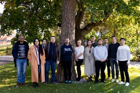 Group members standing around a tree.