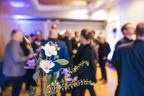 Valkoinen kukka edessä, ihmisiä taustalla