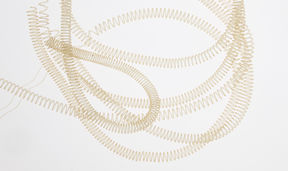 Coiled gold-coloured nylon filaments arranged randomly on a white background.
