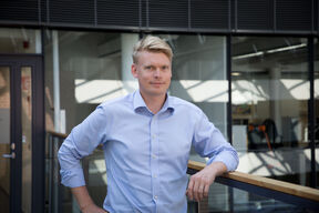 Lauri Saarinen in a light blue shirt leans against a railing in a modern building.