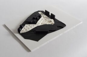 A 3D model with black and white sections resembling buildings on a terrain, placed on a white rectangular base.