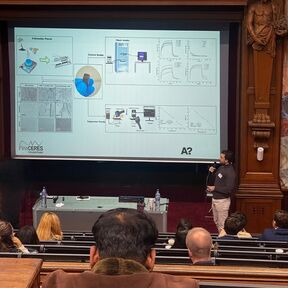 A person is presenting slides in an auditorium. The audience is seated. The presentation title reads 'FinnCERES'.