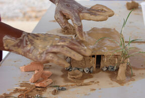 Hands creating a home of clay