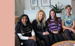 Neljä henkilöä istuu sohvalla olohuoneessa, pöydällä heidän edessään on palapelejä. Taustalla kaksi kehyksiä ja kasvi.