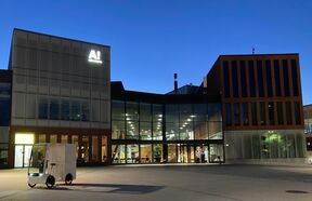 Modern glass and brick building at dusk with a small white electric cargo bike in front
