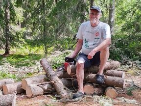 Eero Seuna sits in the forest on the logs he has sawn.