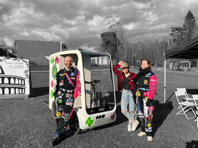Three students pose by a sticker-covered cargo bike at an outdoor Aalto Open Air 2026 event