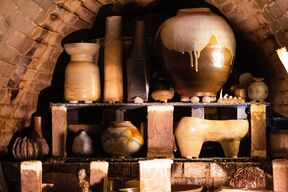 Shelves inside a Anagama kiln filled with assorted clay pots, vases and sculptures in earthy tones