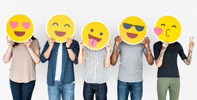 Five people holding large yellow emoji faces in front of them, standing side by side against a white background