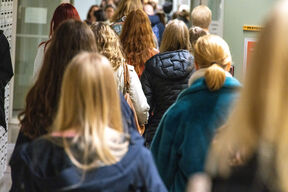 Students are walking down an Aalto university corridor with their backs to the camera.