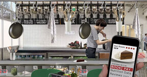 Modern kitchen with a cook, hanging pans and a phone showing a chocolate brownie review