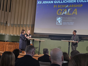 Three speakers at tall tables on a stage during the PI Scholarship Gala, facing an audience in a hall