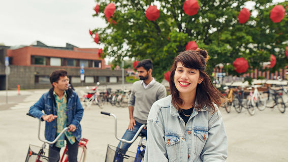 Three students with bicycles in front of Väre building, Aalto University