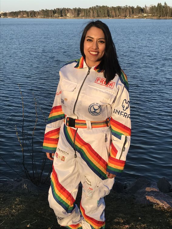 Angelica Mendez standing by a lake in student overalls.
