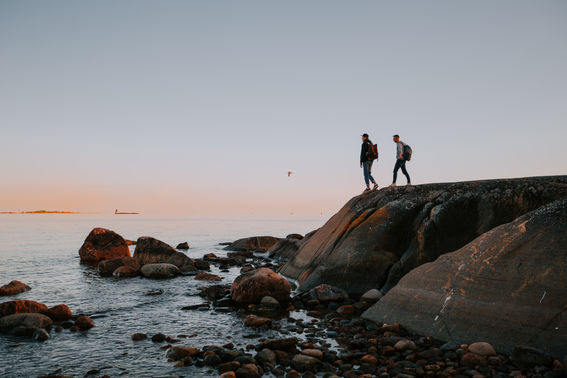 Pihlajasaari Island, two men standing on a cliff looking out at the sea during sunset.