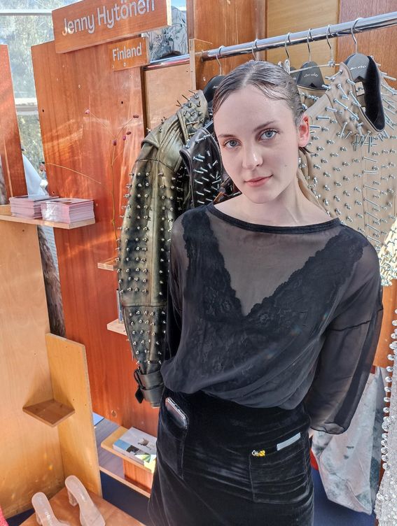 A lady in black clothing posing in front of her fahion collection